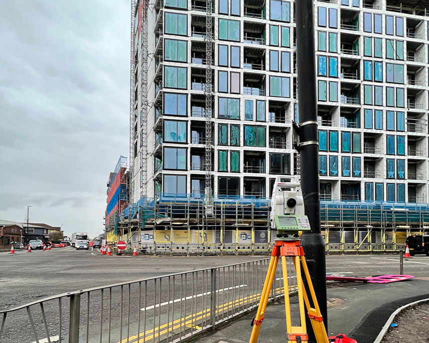 A laser scanner in the foreground with a tower block under construction in the background