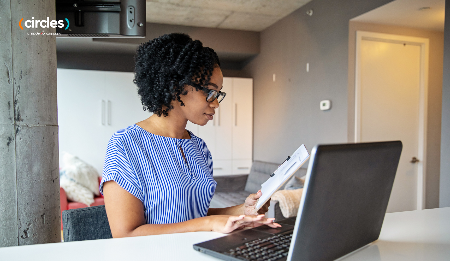 Women working at a desk with a laptop and reading a notepad 