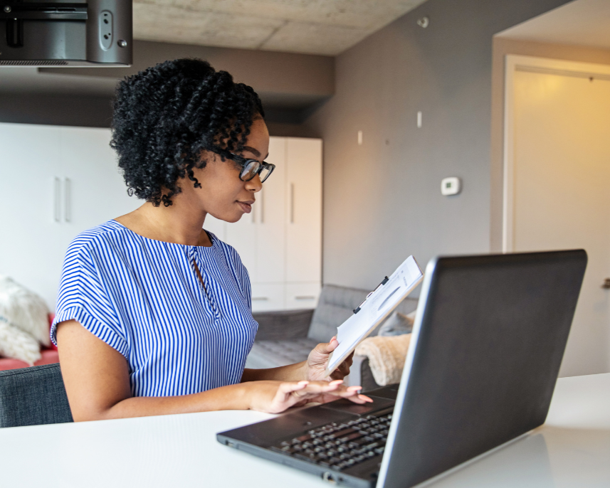 Women working at a desk with a laptop and reading a notepad 
